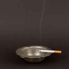 Burning Cigarette In An Old Tin Ashtray