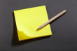 Yellow sticker block note on blackboard and pencil