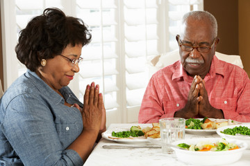 Senior Couple Saying Grace Before Meal At Home