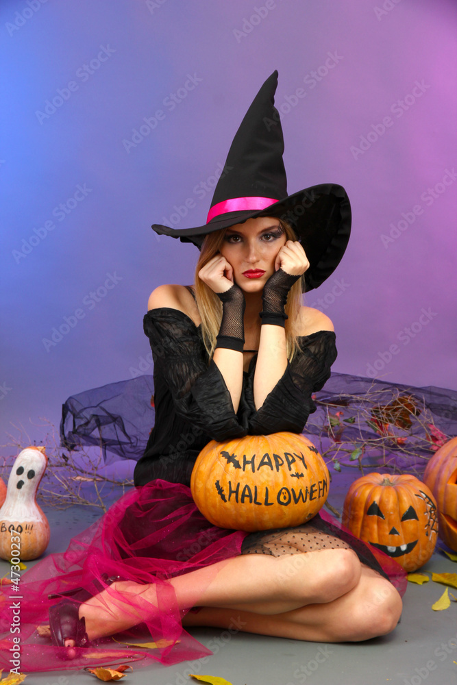 Halloween witch holding pumpkin on color background