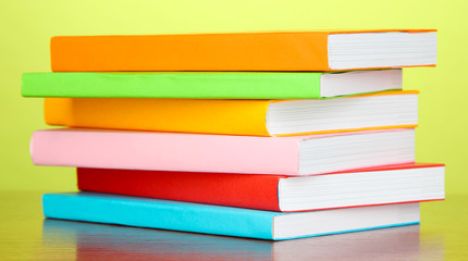 Stack of multicolor books   on green background
