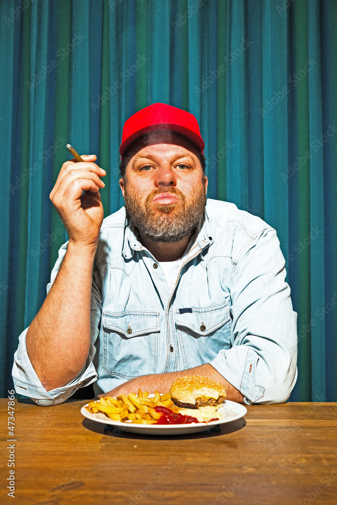 guy eats cigarette Man with beard and eating fast food meal and smoking cigar. Stock Photo