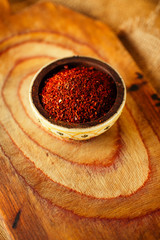 red hot chillies pepper  flakes in bowl on wooden board  backgro