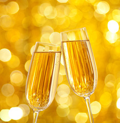 Wall Mural - Two glasses of champagne with lights in the background.