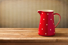 Red Jug With Dots On Wooden Table Over Vintage Background