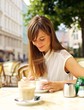 © Jacob Lund - Smiling Woman Having Coffee at a Cafe