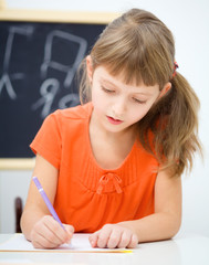 Wall Mural - Little girl is writing using a pen