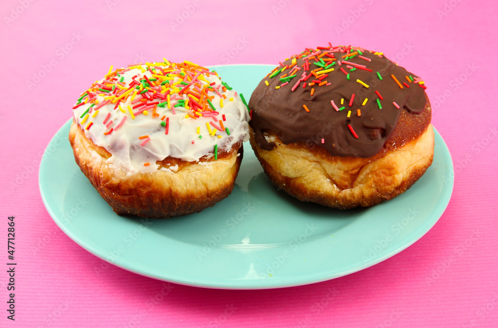 Tasty donuts on color plate on color background
