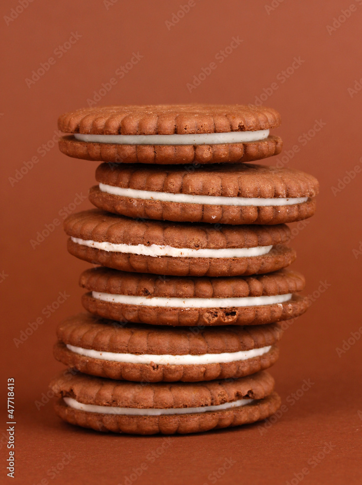 Chocolate cookies with creamy layer on brown background