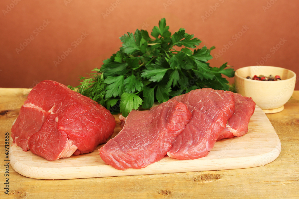 Raw beef meat with spices on wooden table on brown background