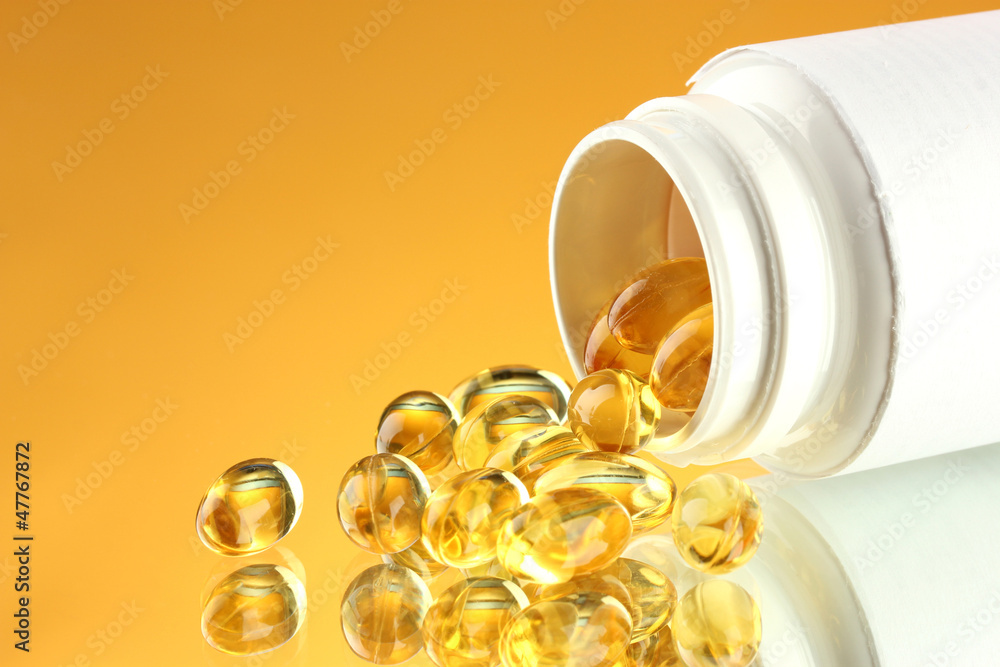 Capsules in bottle, on yellow background