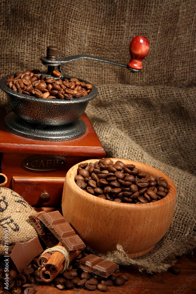 Coffee grinder and cup of coffee on burlap background