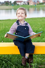 Веселый и милый мальчик в парке читает книгу