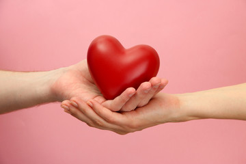 Poster - Red heart in woman and man hands, on pink background