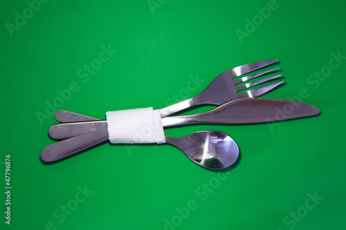 Board z aluminiowym obramowaniem Stół służący nóż, łyżka, widelec na zielonym tle.