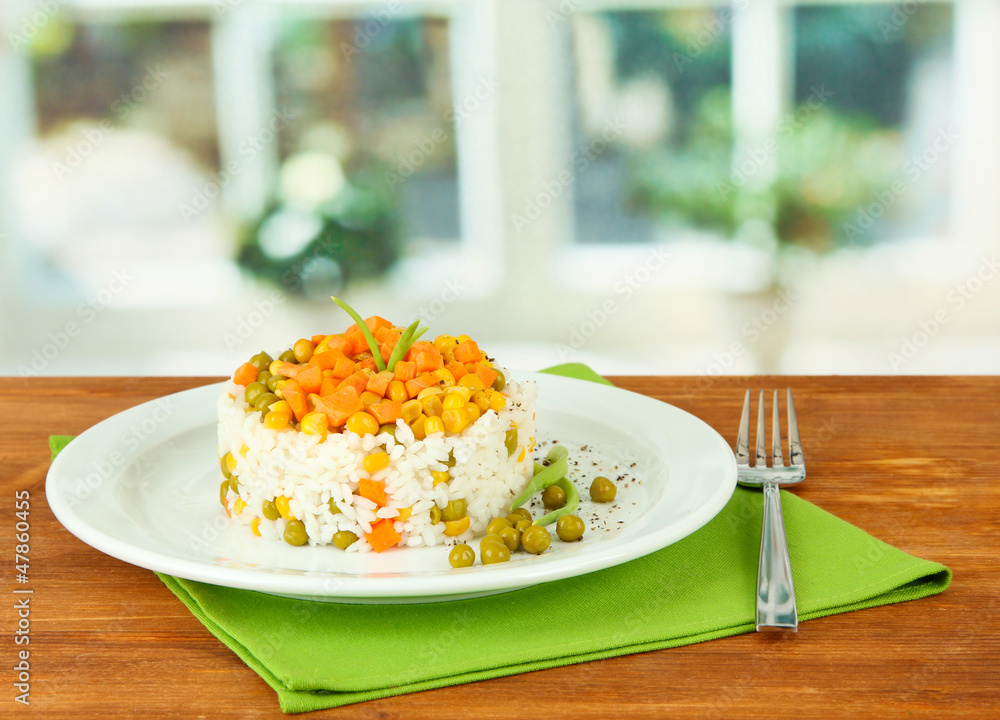 Risotto on plate on wooden table on bright background
