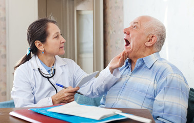 Wall Mural - mature doctor looks the mouth of  patient