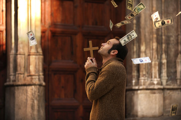 Man praying and money falling from the sky