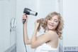 © Wisky - Happy woman with hairdryer in bathroom
