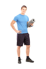 Full length portrait of a male athlete holding a mat