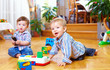 © Olesia Bilkei - two cute baby boys playing with toys at home
