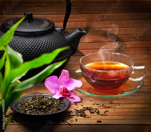 Fototapeta na wymiar Arrangement aus Teekanne, Teeglas grünem Tee und Orchidee