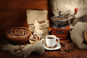 Poster - Coffee grinder and cup of coffee on brown wooden background