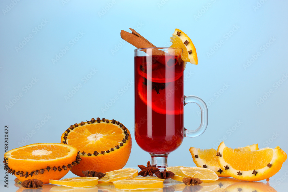 Fragrant mulled wine in glass with spices and oranges around