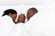 © michaeljung - african american family sleeping on bed