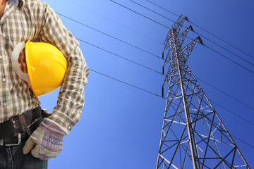 Electrician and high voltage power pylon against blue sky