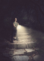 Wall Mural - woman holding a glowing bible in the forest