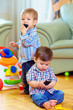 © Olesia Bilkei - two cute baby toddlers explore mobile phones at home