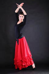 Attractive spanish young woman dancing flamenco over black backg