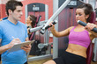 © WavebreakmediaMicro - Trainer noting progress of woman using weights machine