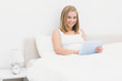 © WavebreakmediaMicro - Portrait of smiling woman using digital tablet in bed