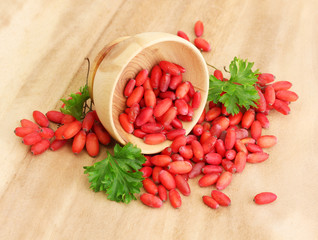 Sticker - ripe barberries in wooden bowl with green leaves, on table