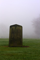 Single gravestone in a spooky graveyard on a foggy day