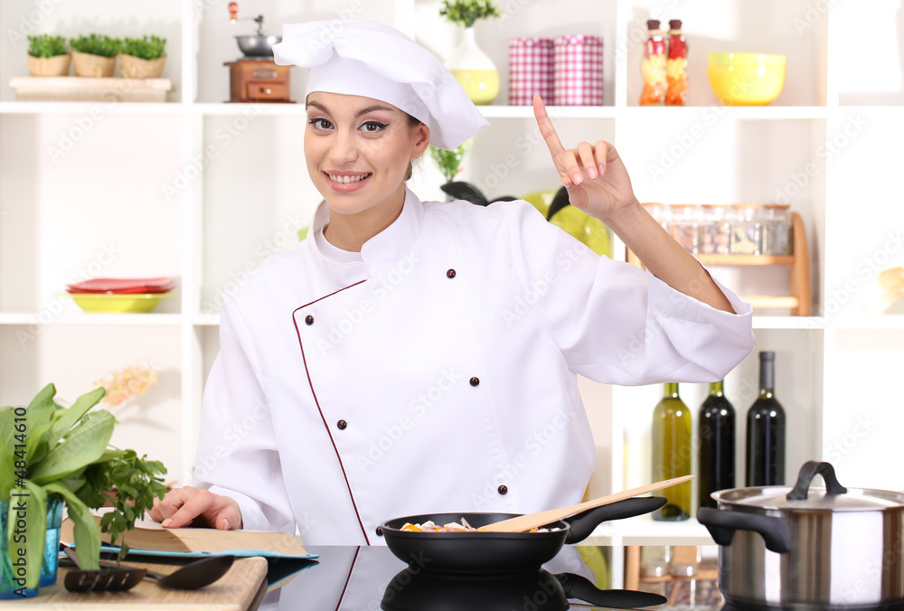 Young woman chef cooking in kitchen