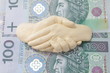 Uścisk dłoni nad banknotami PLN