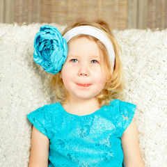 Wall Mural - Curious smiling child girl with blue flower