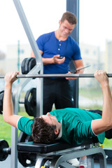 Wall Mural - Trainer und Mann im Fitnessstudio