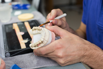 Wall Mural - Closeup of a dental technician applying porcelain to a mold