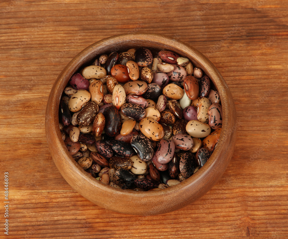 Wooden bowl with beans on wooden background