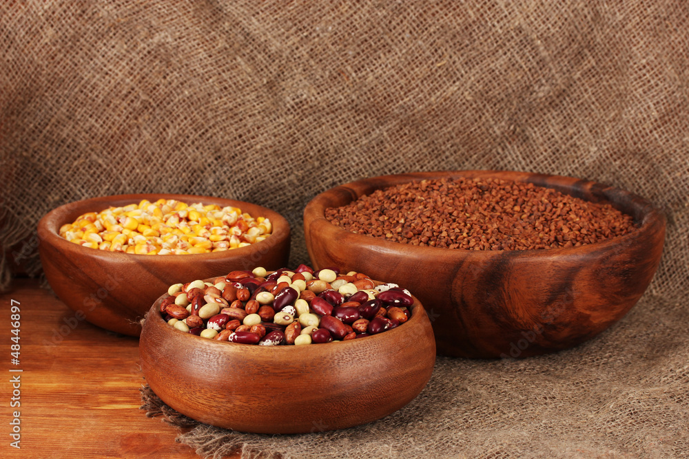 Raw corn,buckwheat and beans in wooden bowls