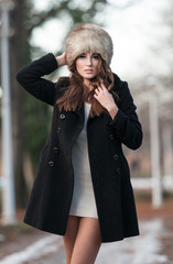 young woman wearing coat walking down the street, cold winter