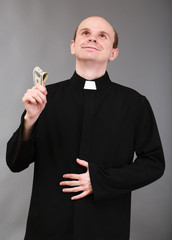 Wall Mural - Young pastor with money on gray background
