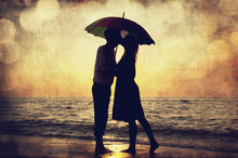 Couple Kissing Under Umbrella At The Beach In Sunset. Photo In O