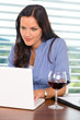 © CandyBox Images - Young businesswoman relaxing home wine surfing internet