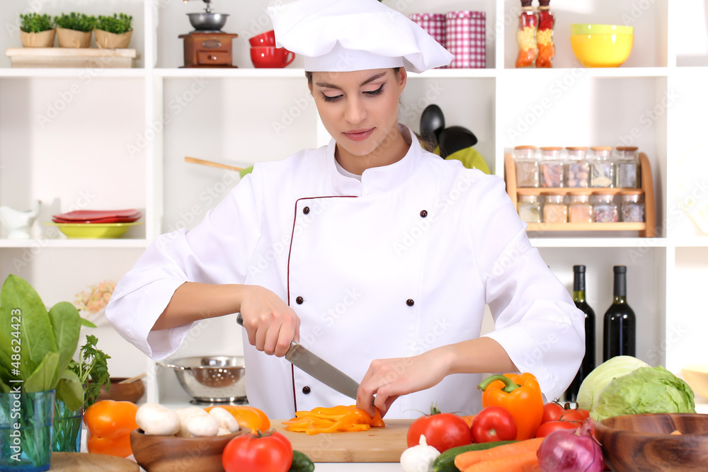 Young woman chef cooking in kitchen