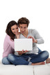 © auremar - Young couple on sofa with laptop